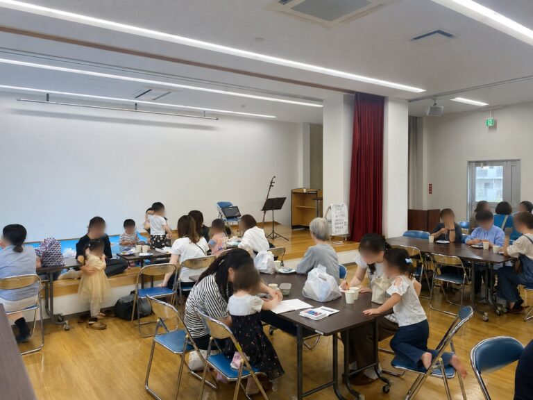 公民館の広間でテーブルを囲む親子と地域の方々